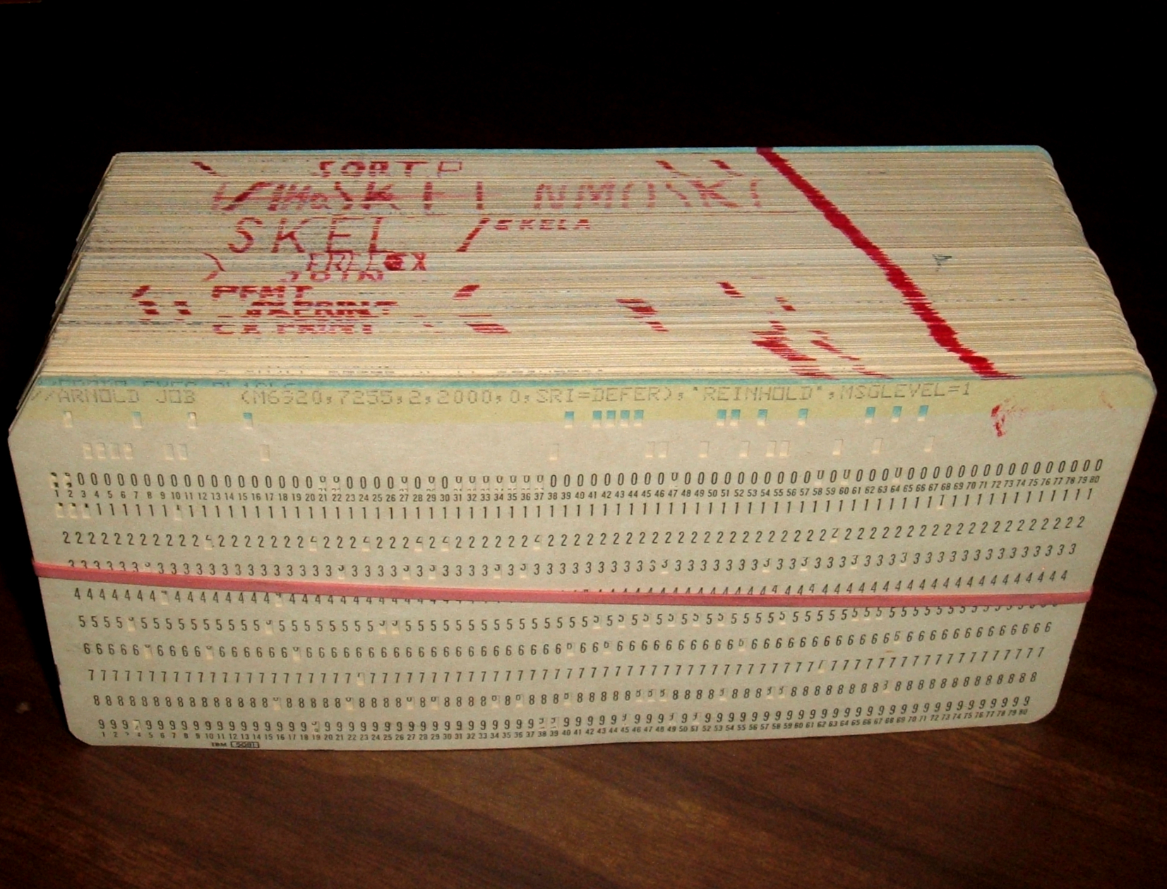 Stack of punch cards held together with a rubber band and marked with a diagonal red line for sorting